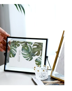 Detail of hand adjusting a modern geometric metal photo frame in a bright interior