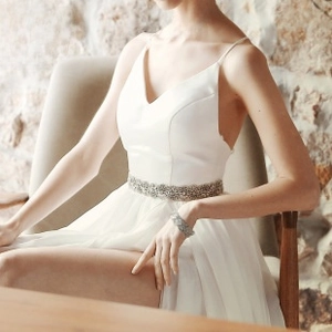 Detail view of sparkly bridal rhinestone belt styled with a white satin wedding dress