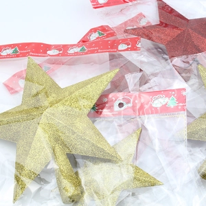 Detail of glittered star tree toppers in gold and red with festive holiday packaging