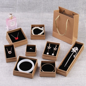 Various sizes of black kraft paper jewelry boxes and matching gift bags on linen