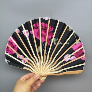 Detailed view of black fabric fan with pink floral prints and natural bamboo ribs