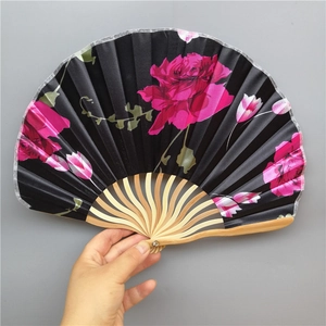 Detail of hand holding an open bamboo folding fan with black fabric and pink floral prints