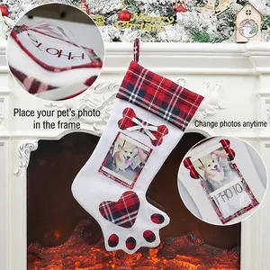 Custom dog paw Christmas stocking with photo frame and red plaid hanging on a fireplace