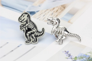 Macro detail of dinosaur skeleton pins in silver metal and black enamel on artistic background