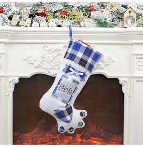 Detail of white dog paw Christmas stocking with blue plaid trim and photo insert pocket