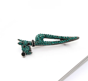 Detailed close-up of a silver poodle brooch encrusted with emerald green rhinestones