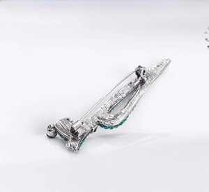 Macro shot of vintage silver brooch back with detailed pin clasp and green rhinestones