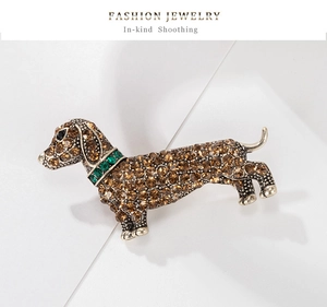 Macro detail of retro dachshund brooch with amber rhinestones and a green crystal collar