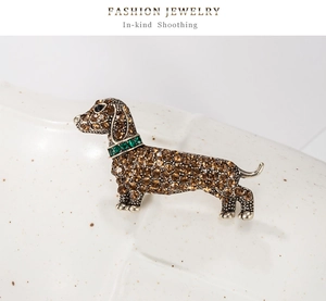 Detailed view of dachshund dog brooch with champagne rhinestones and green emerald collar