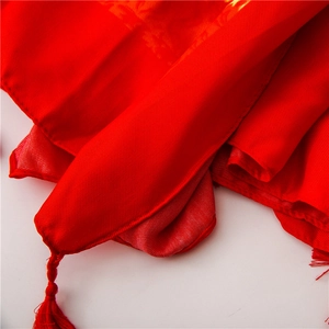 Detail of red silk shawl with golden jacquard patterns and elegant fringe trim