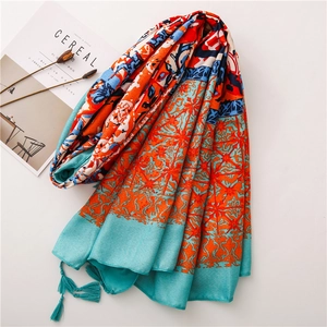 Detail of ethnic print shawl with vibrant orange tassels on clean white background