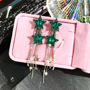 Detailed macro view of star-shaped earrings with green crystals and pearl fringe tassels