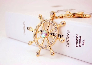 Close-up of golden nautical helm keychain with sparkling crystals on a book