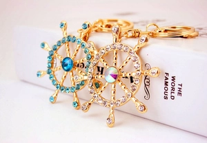 Close-up of golden nautical helm keychains with blue and clear crystal rhinestones