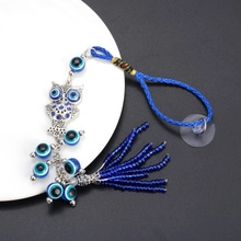 Macro view of owl charm with blue evil eye bead and tassel for home or car decor