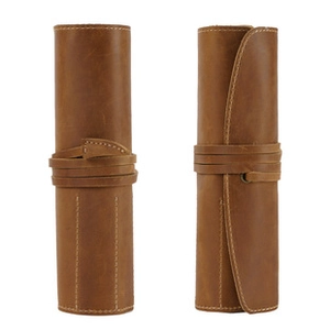 Detail of a brown genuine leather roll pouch showing its buckle and tied strap closure