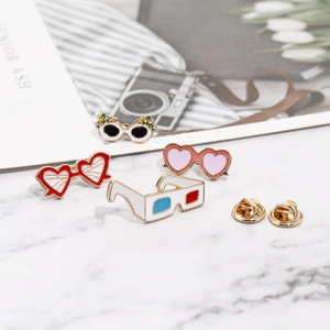Detailed view of four colorful enamel eyewear brooches on a marble surface backdrop