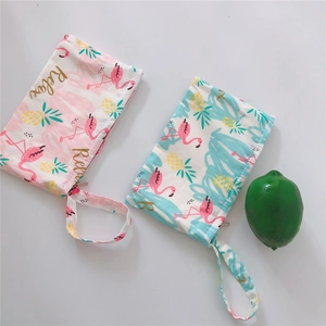 Close-up of canvas phone pouch with flamingo print, wrist strap and gold Relax text