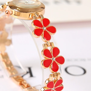 Detailed close-up of golden clover bracelet watch with red enamel flower links