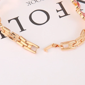 Detail shot of the golden clover bracelet watch band with red enamel and folding clasp