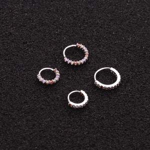 Boucles d'oreilles créoles en cuivre argenté avec zircons colorés sur fond noir