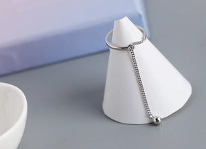 Macro shot of S925 sterling silver chain tassel ring with polished metal bead on stand