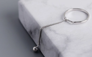 Macro view of minimalist silver bead tassel ring with elegant metallic shine on marble