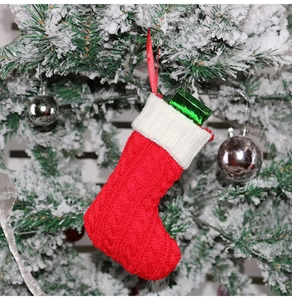 Detail of red knit Christmas stocking with white cuff hanging on a snowy Christmas tree