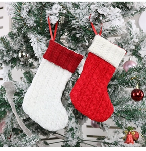 Detail of red and white knit Christmas stockings hanging on snow-covered pine branches
