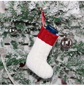 Close-up of red and white knitted Christmas stocking hanging on a snow-covered tree branch