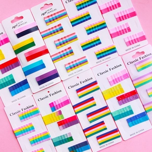 Flat lay view of colorful rainbow and glitter metal BB hair clips on pink background