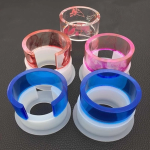 Detail of DIY silicone molds showing finished resin bracelets in various colors on black