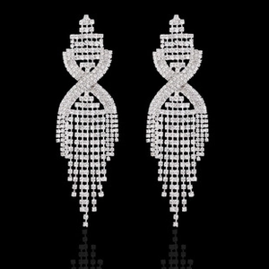 Detailed close-up of long silver tassel earrings with geometric zircon knots and fringe