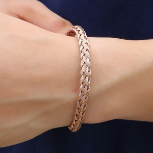 Bracelet jonc torsadé en acier inoxydable or rose porté au poignet féminin