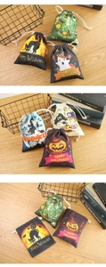 Close-up of Halloween linen gift bags with pumpkin, ghost, and witch patterns on wood