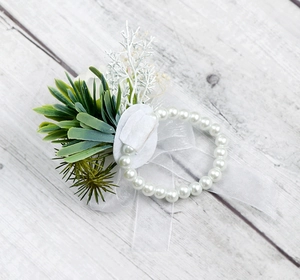 Dettaglio del corsage da polso nuziale con nastro di seta bianco e decorazioni di verde sintetico