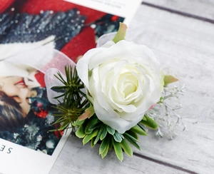 Dettaglio fiore all'occhiello con rosa bianca, piante grasse e nastro su tavolo grigio