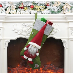 Détail d'une chaussette de Noël tricotée avec gnome suspendue sur une cheminée blanche