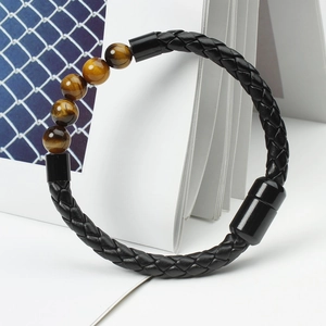 Detail of men's braided leather bracelet featuring natural tiger eye beads and magnetic clasp