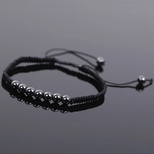 Macro shot of hematite beads on a black braided cord bracelet with mirror reflection