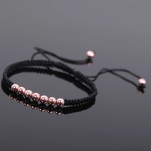 Macro view of adjustable black braided rope bracelet with polished rose gold beads