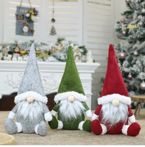 Tre gnomi natalizi nordici in grigio, verde e rosso seduti vicino a un caminetto