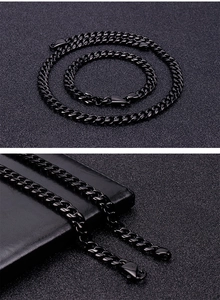 Dettaglio del set collana e bracciale a catena cubana in acciaio nero su trama scura