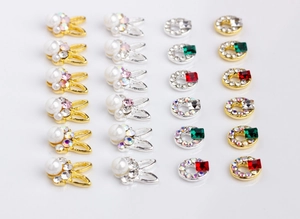 Detail of alloy nail charms featuring pearl rabbits and square glass gemstones with rhinestones