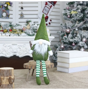 Green Christmas gnome doll with striped legs placed on a wooden stool in a festive home setting