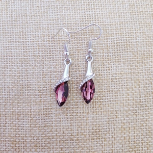Close-up of elegant drop earrings featuring purple teardrop crystals and silver hooks