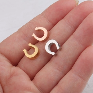 Polished stainless steel horseshoe charm beads in gold, silver, and rose gold on a hand