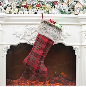 Close-up of red and green plaid Christmas stocking with faux fur hanging on fireplace