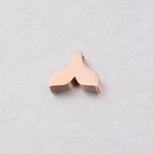 Macro detail of rose gold mermaid tail pendant with polished mirror finish for DIY jewelry