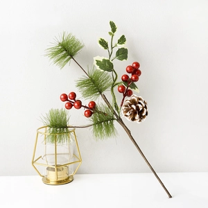 Detailed view of artificial pine needles with festive red berries and snowy pine cones